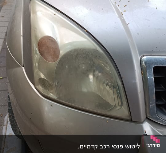 פנס קדמי מלוכלך של רכב עם גריל מתכתי